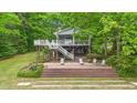 Inviting lake house with elevated deck, stairs and tiered brick patio with lounge seating at 104 Pontiac Cv, Louisburg, NC 27549