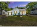 Charming home with white brick, turquoise door, wood shutters, and a manicured lawn at dusk at 105 N 11Th St, Erwin, NC 28339