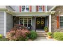 Inviting front porch showcasing decorative wreaths, colorful foliage, rocking chair, and a stylish double-door entrance at 110 Pebble Creek Dr, Franklinton, NC 27525