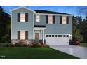 Charming two-story home with blue siding, black shutters, stone accents, and a two-car garage at 1100 Landen Creek Ln, Zebulon, NC 27597