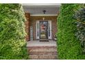 Inviting front porch with brick columns, a 'Welcome' sign, and lush green shrubbery at 114 Bell Tower Ct, Elon, NC 27244