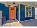 Inviting front porch showcasing the blue wood facade, contrasting orange door, and a large window with white trim at 127 Post Oak Rd, Chapel Hill, NC 27516