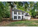 Charming two-story home with black shutters and a brick chimney surrounded by mature trees at 1609 Falls Ct, Raleigh, NC 27615