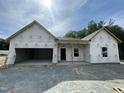 New construction home featuring a two car garage, visible studs and house wrap; ready for finishing at 445 Olivia Crossing Ct # 22, Four Oaks, NC 27524