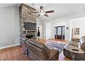 Bright living room with a stone fireplace, modern ceiling fan, and hardwood floors offering a cozy atmosphere at 494 Asset Pkwy, Sanford, NC 27332