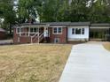Charming brick home with a covered porch, black roof and gutters, carport, and a concrete driveway at 502 Burton St, Fuquay Varina, NC 27526
