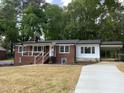 Charming brick home with a covered porch, black roof and gutters, carport, and a concrete driveway at 502 Burton St, Fuquay Varina, NC 27526