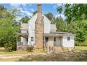 Back view of a two-story home featuring a stone chimney and a small, covered porch accessible by stairs and a lift at 5062 Dorsey Rd, Oxford, NC 27565