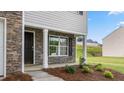 Welcoming covered front porch with stone detail and manicured garden at 522 Lochalsh Dr, Gibsonville, NC 27249