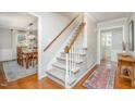 Bright foyer featuring a staircase with white railings, hardwood floors, and views into dining room at 5312 Hallmark Rd, Durham, NC 27712