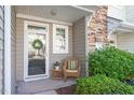 Inviting front porch with a wicker chair, stone accents, and glass front door at 5912 Hourglass Ct, Raleigh, NC 27612