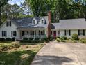 Inviting white home with a red front door, dormer windows, landscaping, and a spacious driveway at 7401 Walnut Grove Ln, Zebulon, NC 27597
