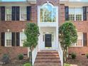Close-up of the brick home's front door with sidelights, framed by manicured shrubs at 102 Downing Forest Pl, Cary, NC 27519