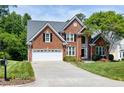 Well maintained brick home with a two car garage, mature trees, and a lush green lawn at 105 Bardsey Ct, Cary, NC 27513
