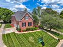 Aerial view of a red brick home with manicured lawn, landscaping, driveway, and view of the neighborhood at 11916 Deneb Ct, Raleigh, NC 27614