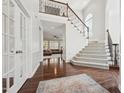 Bright foyer with hardwood floors, staircase with iron railing, and view into a living room with large windows at 11916 Deneb Ct, Raleigh, NC 27614