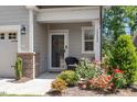 Inviting front porch with black wicker chair and beautiful floral landscape at 12404 Huntley Chase Dr, Durham, NC 27703