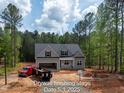 Charming home with gray siding, black shutters, an attached garage, surrounded by lush greenery at 125 Purslane Dr, Franklinton, NC 27525