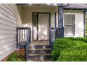 Covered front porch with classic white door, dark trim, and manicured shrubs at 17 Nicklaus Way, Clayton, NC 27520