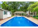 In-ground swimming pool surrounded by an outdoor kitchen, covered patio, and storage shed at 204 Random Ln, Burlington, NC 27215