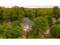 Aerial view of a green roofed two-story home nestled among lush trees in a serene neighborhood at 223 Hall Ave, Burlington, NC 27217