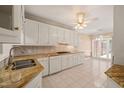 Bright kitchen featuring granite countertops, tile backsplash, white cabinets, and stainless steel sink at 2303 Upper Oaks Way, Raleigh, NC 27615