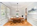 Elegant dining room featuring hardwood floors, tray ceiling, and stylish chandelier over a wood table at 2728 Cameron Pond Dr, Cary, NC 27519