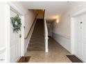 Hallway with tile flooring, a staircase, and white trim highlighting the entrance to residential units at 412 Waterford Lake Dr, Cary, NC 27519