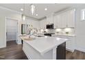 Bright kitchen features white cabinets, stainless steel appliances, and a large island with quartz countertop at 425 Shadow Falls Dr, Wendell, NC 27591