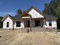 New construction home featuring a brick foundation, black windows, and architectural roof against a clear blue sky at 5021 Mitchell Town Rd, Youngsville, NC 27596