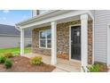 Inviting front porch with stone accents, white columns, and a black front door at 525 Lochalsh Dr, Gibsonville, NC 27249