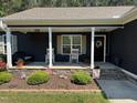 Cozy front porch with rocking chairs and stone accents, enhanced by a landscaped flower bed at 60 Northdale Ct, Louisburg, NC 27549