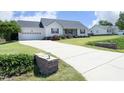 Picture shows the house's long, paved driveway leading to a two-car garage and landscaped front yard at 74 Pedernales Dr, Smithfield, NC 27577