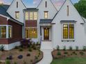 Inviting home with white brick, striking black trim, and a welcoming entrance framed by mature landscaping at 9004 Meadow Pointe Ct, Wake Forest, NC 27587