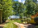 Lush backyard with mature trees and walkway leading to scenic lake views, creating a serene outdoor space at 901 Edgewater Dr, Garner, NC 27529