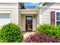 Close-up of the front door, framed by vibrant green shrubs and colorful foliage at 1004 Gold Cir, Mebane, NC 27302