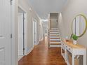 Inviting hallway with hardwood floors, white trim, and a staircase leading to the upper level at 115 Moss Creek Pl, Fuquay Varina, NC 27526