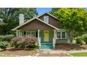 Craftsman-style home with stone chimney, covered front porch, and a yellow front door with well-maintained garden at 209 E Winston St, Youngsville, NC 27596