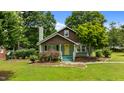 Charming home with stone chimney, covered porch, yellow door, landscaped garden, and well-maintained lawn at 209 E Winston St, Youngsville, NC 27596