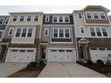 Exterior view of townhomes with two-car garages, varied siding, and decorative stone accents at 2323 Hunter Woods Dr # 566, Apex, NC 27502