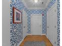Bright hallway with blue patterned wallpaper, hardwood floors, and crisp white doors and trim at 2701 Glenwood Gardens Ln, Raleigh, NC 27608