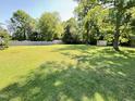 Expansive backyard featuring lush green grass, mature trees, and a storage shed at 2710 Delaney Dr, Burlington, NC 27215