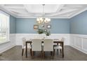 Dining room featuring wainscoting, a coffered ceiling, hardwood floors, and a modern chandelier over the dining table at 277 High Ridge Ln, Pittsboro, NC 27312