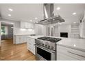 Modern kitchen with stainless steel appliances, white cabinets, large island, and hardwood floors at 3420 Sheridan Dr, Durham, NC 27707