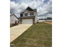New home featuring a two-car garage, stone accents, and a spacious lawn ready for landscaping at 364 Peach Grove Way, Lillington, NC 27546