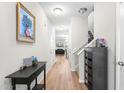 Inviting hallway with hardwood floors, neutral walls, and decoratively adorned table, leading to the living area and staircase at 513 Commons Dr, Holly Springs, NC 27540