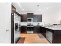 Modern kitchen with dark cabinetry, stainless steel appliances, granite countertops, and hardwood flooring for a modern look at 513 Commons Dr, Holly Springs, NC 27540
