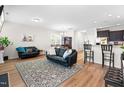 Open-concept living room features two leather sofas, a patterned rug, and flows seamlessly into the dining and kitchen areas at 513 Commons Dr, Holly Springs, NC 27540