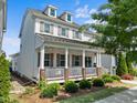 Beautiful white two-story house featuring a cozy front porch with swing, well-maintained lawn, and lovely curb appeal at 5217 Beckom St, Raleigh, NC 27616