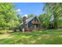 Quaint house with a brick chimney and a wrap-around porch set on a well-manicured lawn at 5346 Deep River Rd, Sanford, NC 27330